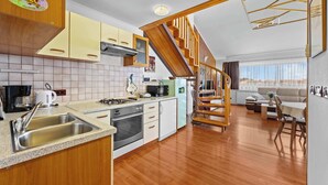 Una cocina con escalera de madera, comedor y vistas a las montañas.