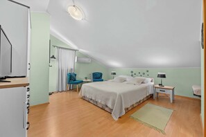 Un dormitorio con cama, escritorio, silla y ventana con cortinas.