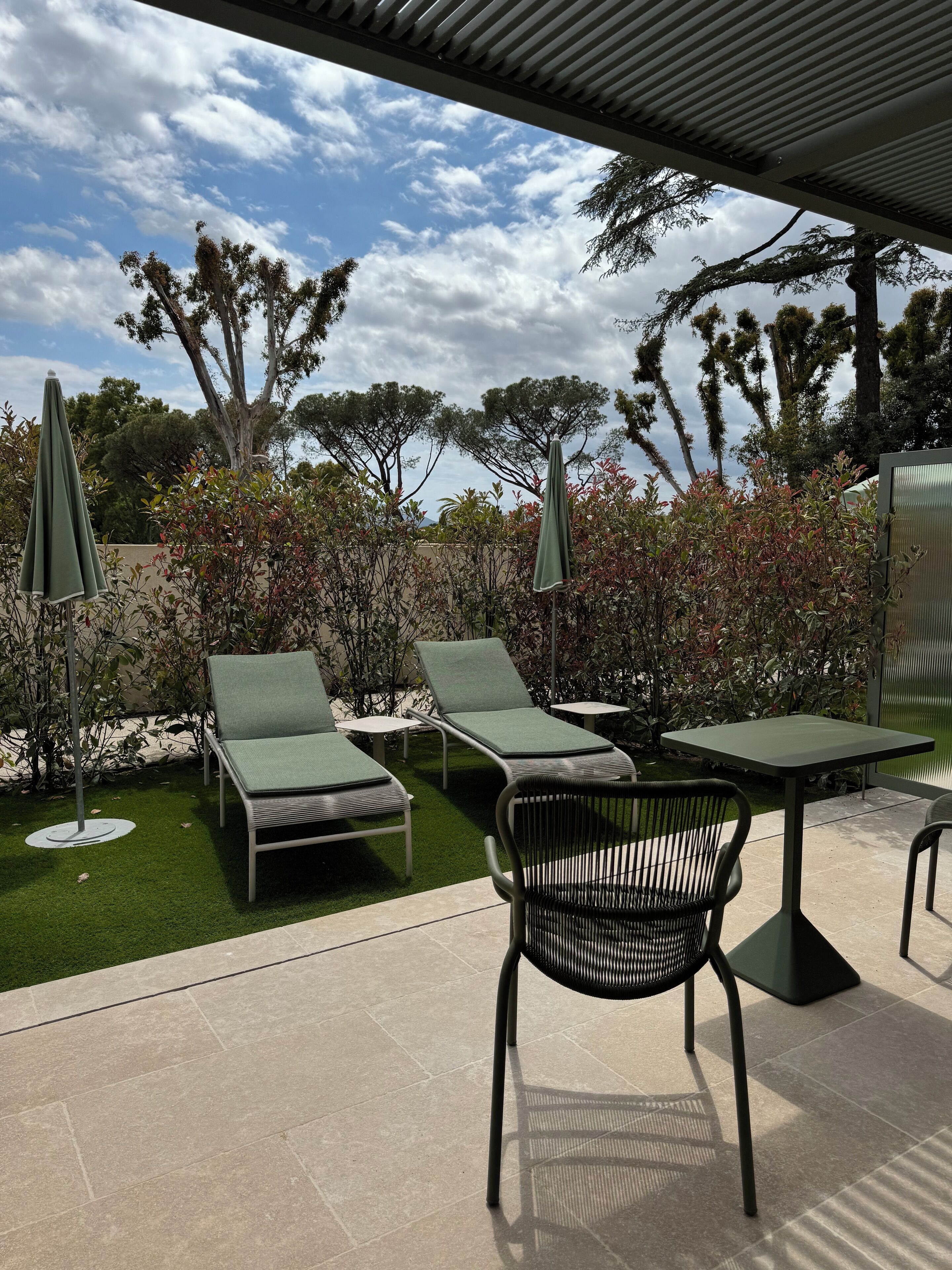 An outdoor patio with lounge chairs, a table, and umbrellas.