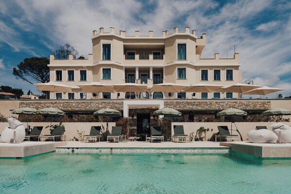 A large, multi-story hotel with a pool area in front. - Hôtel Le Château Rose (Grimaud)