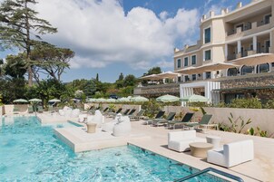 Una piscina al aire libre, sombrillas, sillones reclinables de piscina