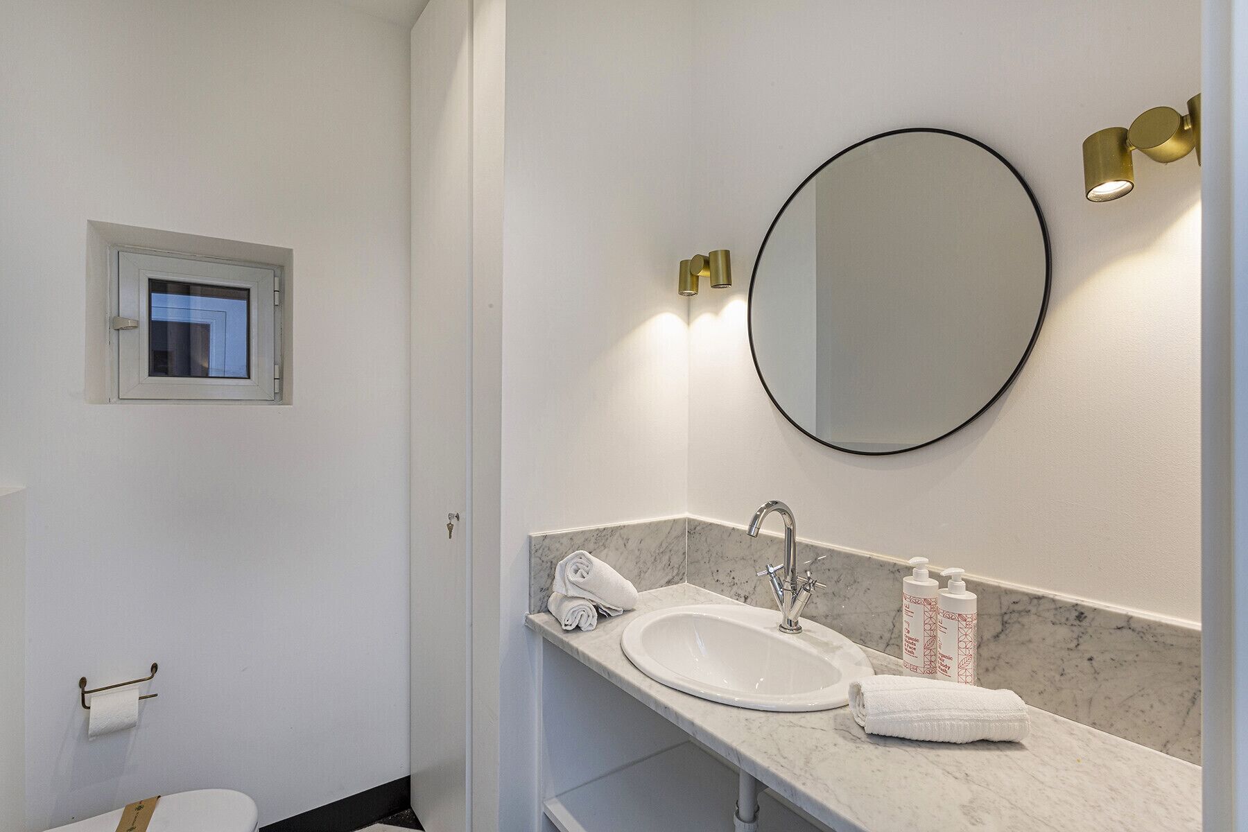 A bathroom with a white sink, a mirror, and a towel rack.