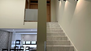 A modern interior with a dining area, a staircase, and a view of the outdoors.