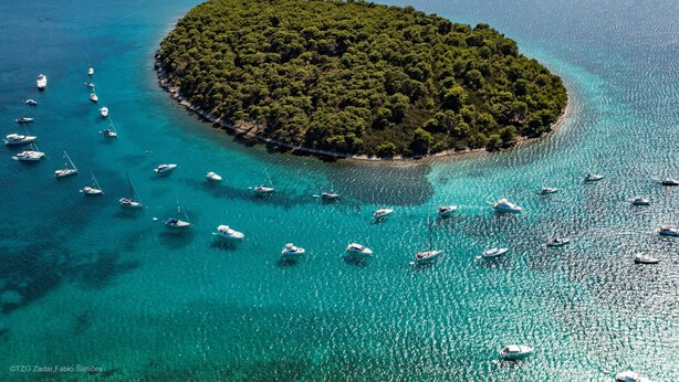 An aerial view of a small island surrounded by turquoise waters with numerous boats anchored around it. - Studio Apartments Darija - A2 (Brgulje)