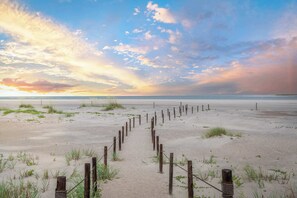 Une plage de sable bordée d’une clôture en bois qui mène à l’eau.