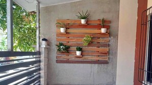 A balcony with a wooden bench, a small table, and a wall-mounted plant shelf. - 3BR Home • Free Netflix + Wi-Fi • Solar Powered (Kabankalan City)