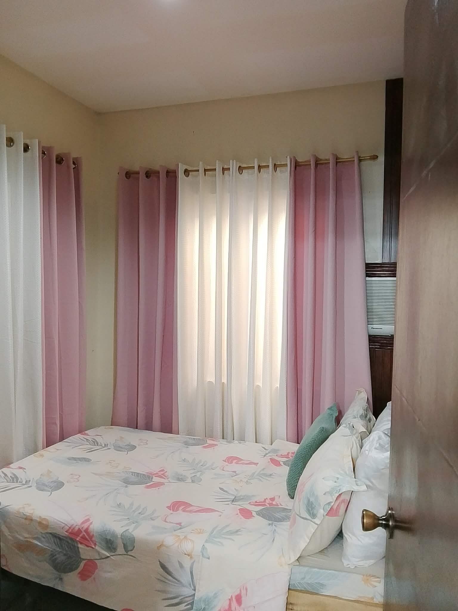 Un dormitorio con cama, cortinas y una puerta.