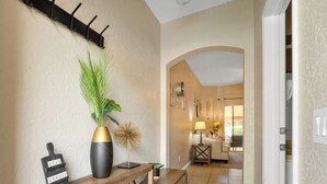 A hallway with a wooden bench, a black vase with a plant, and a sign that reads "STAY AWAY."