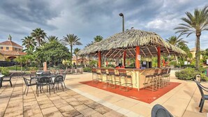 An outdoor patio area with a thatched-roof bar and seating.