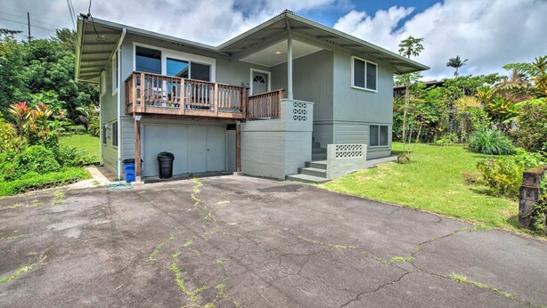 A two-story house with a balcony, a garage, and a well-maintained lawn. - Kai Cottage - A Little Piece of Old Hilo (Hilo)
