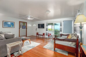 A spacious living room with a sofa, a wooden table, a bed, and a television.