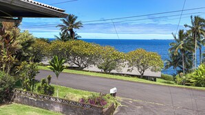 A residential area with a street, a mailbox, and a view of the ocean. - Kai Cottage - A Little Piece of Old Hilo (Hilo)