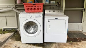A front-loading washer and dryer stacked outdoors with a red basket on top. - Kai Cottage - A Little Piece of Old Hilo (Hilo)