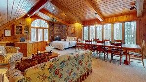 Une cabane chaleureuse avec une chambre à coucher située en mezzanine, un coin repas et un salon doté d’une cheminée.