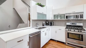 A modern kitchen with white cabinets, stainless steel appliances, a dishwasher, and a built-in oven.