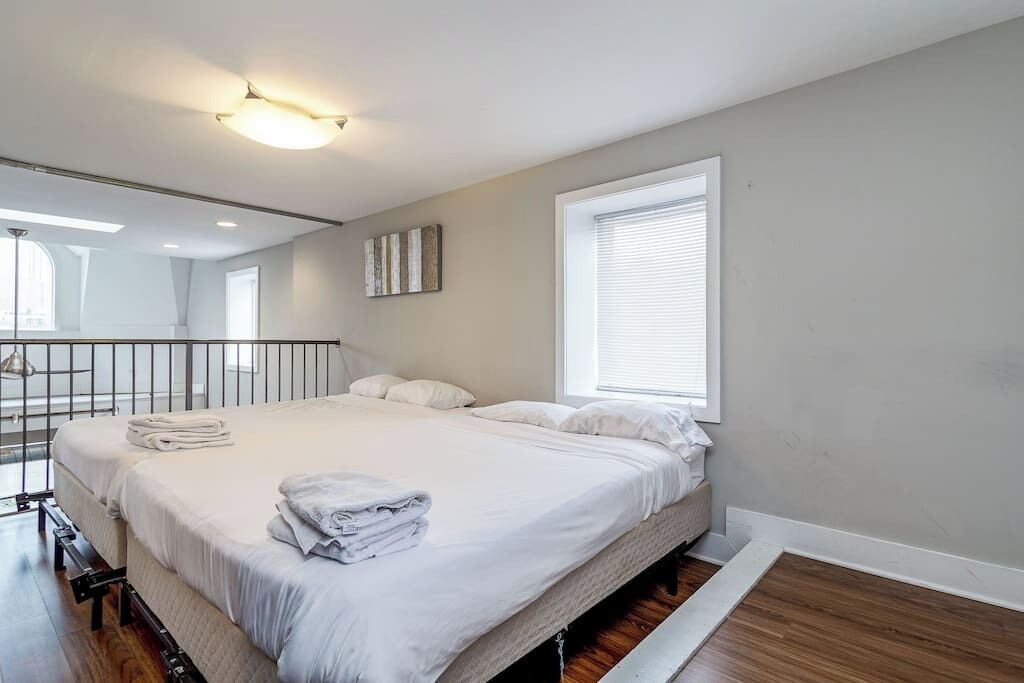 Un dormitorio con una cama grande, una ventana con persianas, una lámpara en el techo y un espejo en la pared.
