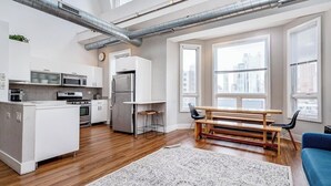 A modern kitchen with white cabinets, stainless steel appliances, and a wooden dining table.