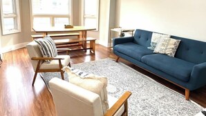A living room with a blue sofa, a wooden coffee table, a striped armchair, and a rug.