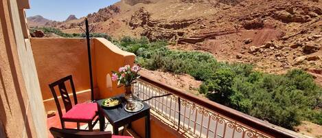 Un balcón con mesa y sillas, con vistas a un paisaje montañoso.