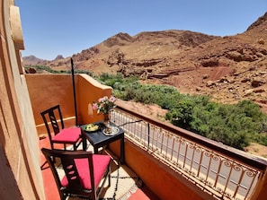 Un balcon avec une table et des chaises, donnant sur un paysage montagneux.