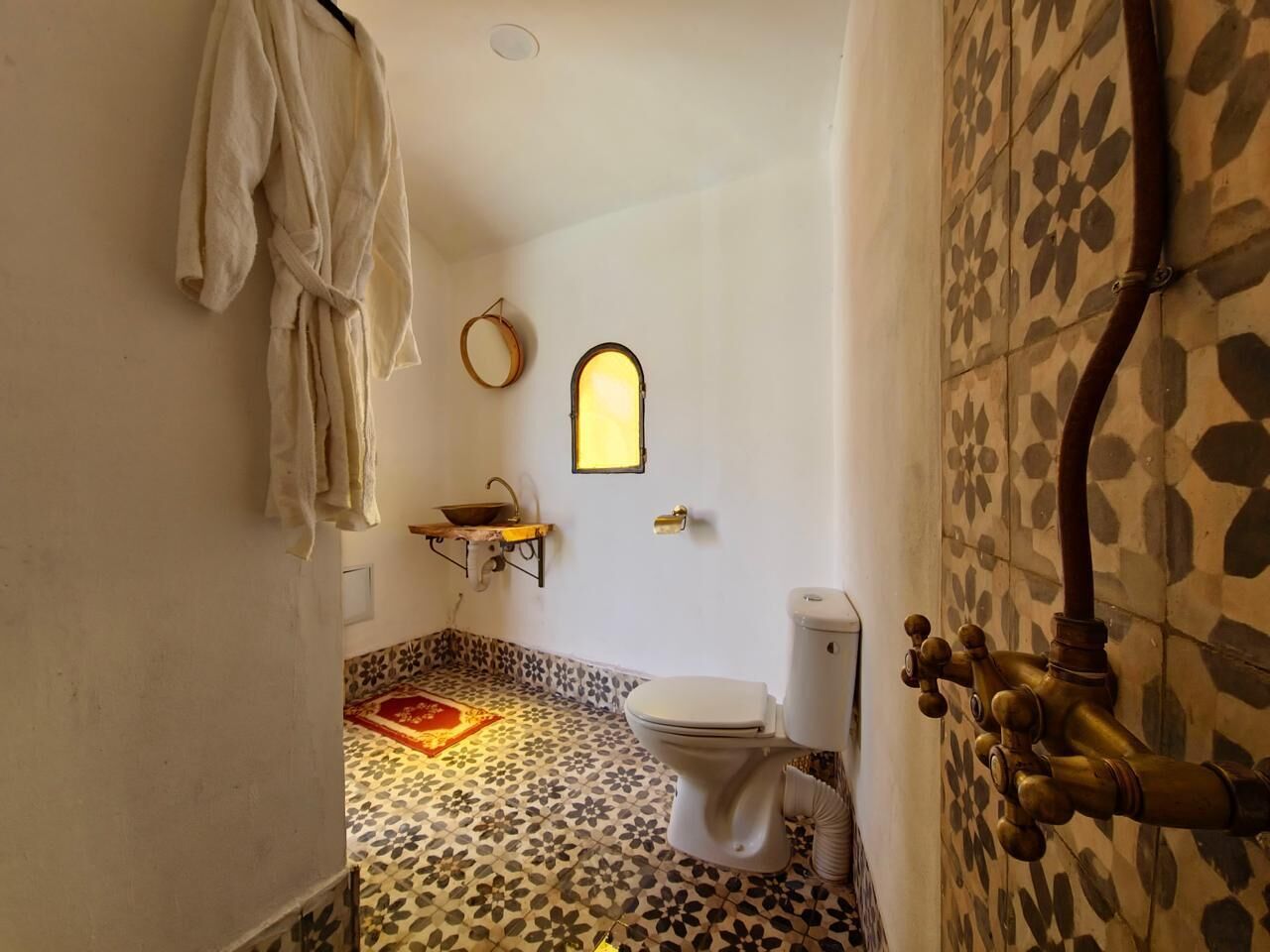 Un baño con inodoro, lavamanos, ducha y piso estampado.