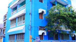 A blue building with balconies, a sign for 'Hotel J.K. Inn', and a motorcycle parked outside. - DhamStay Hotel JK Inn Near SeaBeach Puri (Puri)