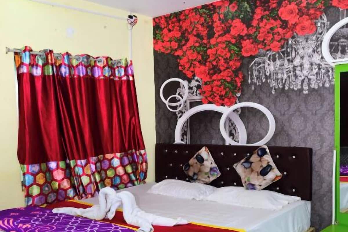 A bedroom with a bed, a ceiling fan, a red curtain, and a wall with a floral pattern.
