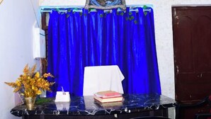 A room with a blue curtain, a table with a vase of flowers, and two chairs with red cushions. - DhamStay Hotel JK Inn Near SeaBeach Puri (Puri)