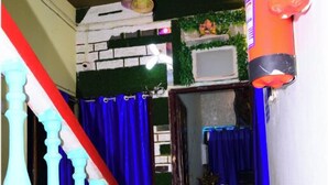 A staircase with teal balusters, red carpet, and blue curtains. - DhamStay Hotel JK Inn Near SeaBeach Puri (Puri)