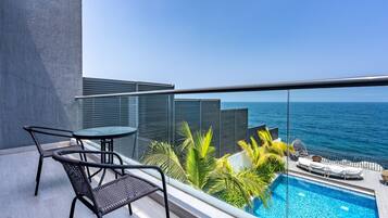 Een balkon met een zwembad, stoelen en uitzicht op zee.