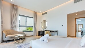 A modern hotel room with a large bed, a sofa, a round mirror, and a desk. - Exclusive 4BR Villa, Lush Garden & Private Pool Facing Panoramic Sea Views (Fujairah)