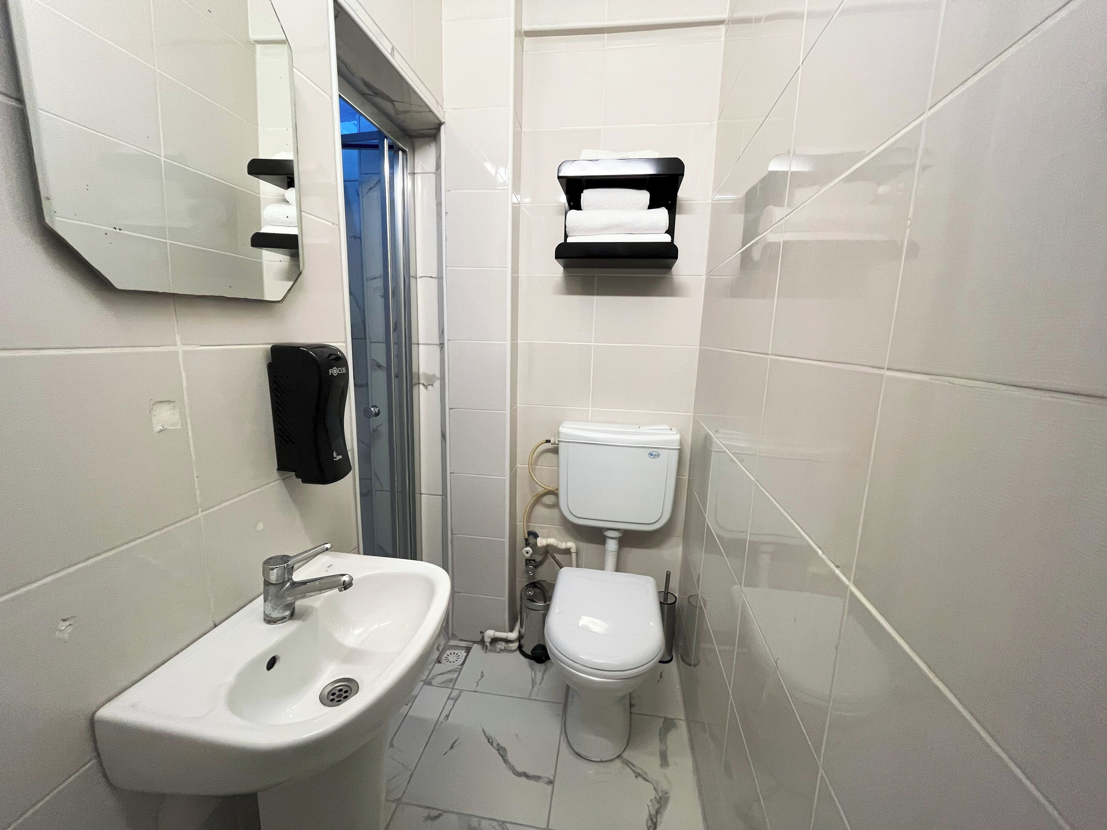 Un baño pequeño con lavamanos, inodoro y toallero.