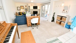 A living room with a piano, a blue sofa, a wooden desk, and a fireplace. - 3 Bedroom 2 Bath Home Close to ND w Fire pit 1155 (South Bend)