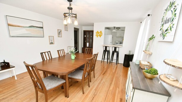 A dining area with a wooden table and chairs, a kitchen in the background, and a framed picture on the wall. - 3 Bedroom 2 Bath Home Close to ND w Fire pit 1155 (South Bend)