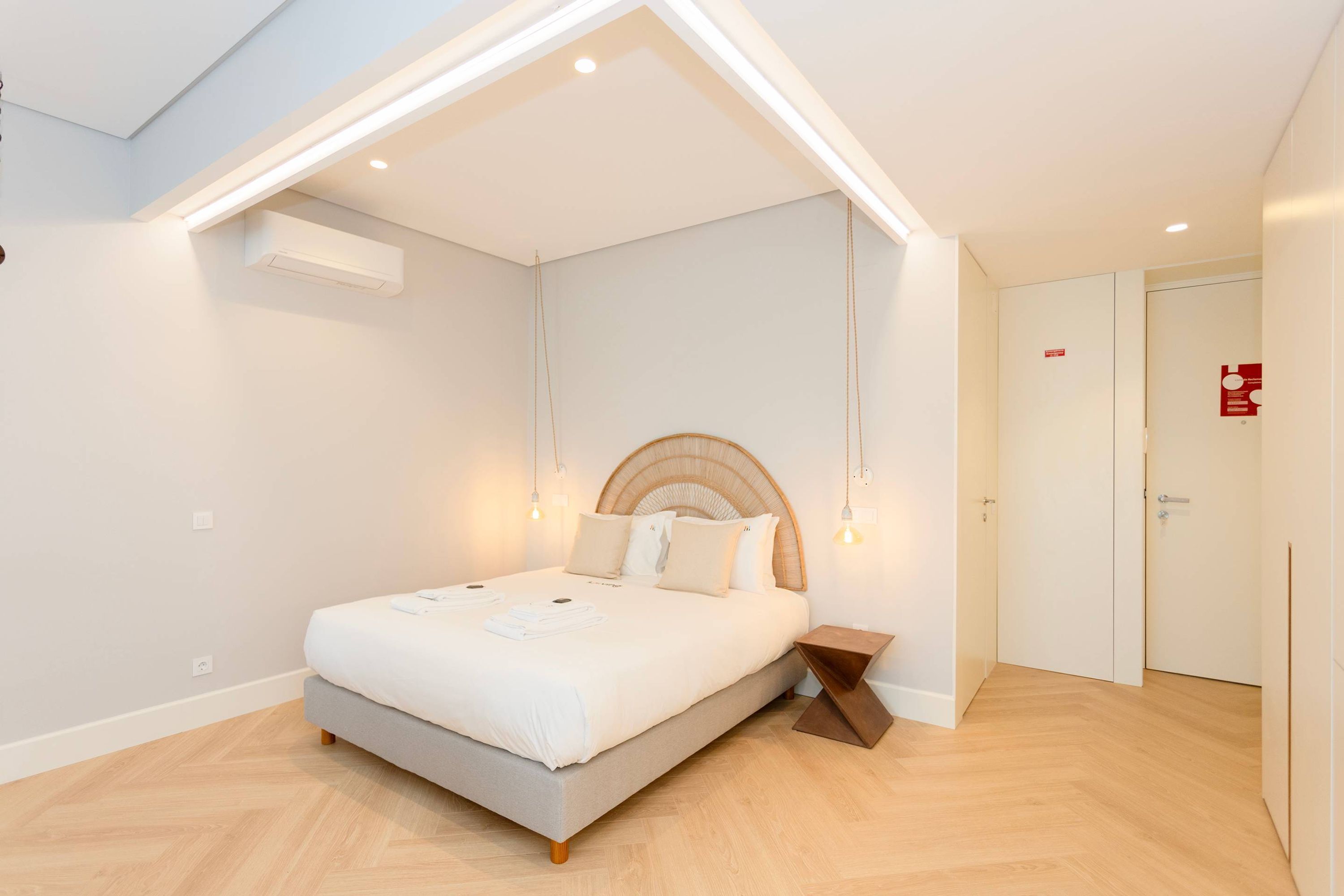 A modern bedroom with a bed, bedside table, and a ceiling light fixture.