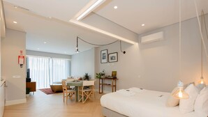 A modern bedroom with a bed, bedside table, and a desk with a chair. - Liiiving in Porto - Luxury Design Apartment M (Porto)
