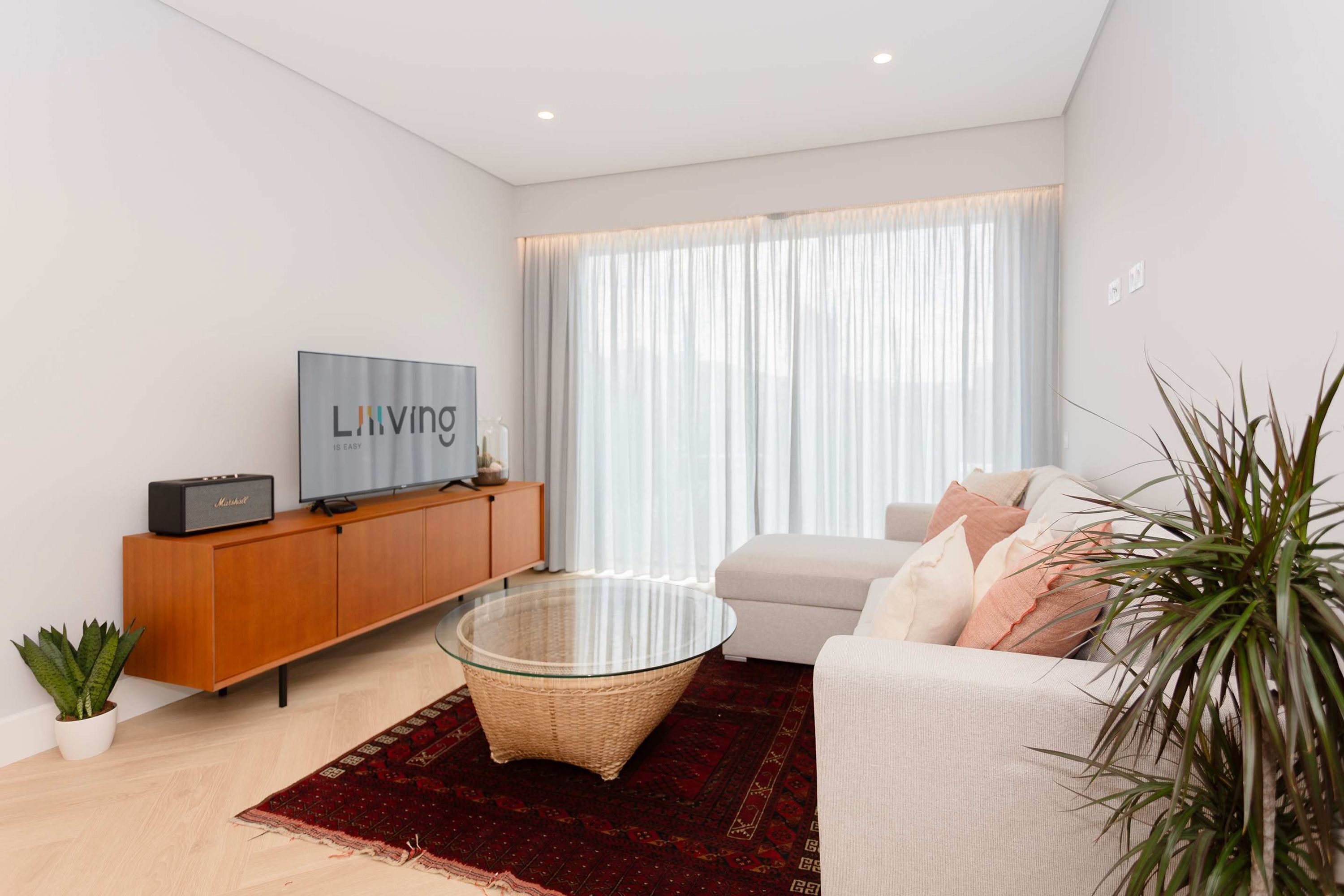Una sala de estar moderna con una mesa de centro de vidrio, un sofá, un televisor y un armario.