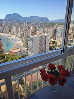 Uma varanda com vista para a paisagem urbana, incluindo edifícios altos e uma praia.