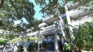 A multi-story residential building with balconies, a gated entrance, and surrounding greenery. - 2 BR Condo with Shared Pool! Sea Grove 202 (Surfside Beach)