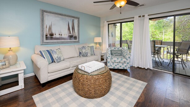 A living room with a sofa, a coffee table, and a chair. There is a painting on the wall and a window with curtains. - 2 BR Condo with Shared Pool! Sea Grove 202 (Surfside Beach)