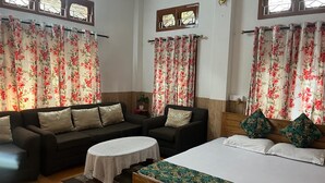 Une pièce comprenant un lit, deux canapés, une petite table et des rideaux à motifs floraux.