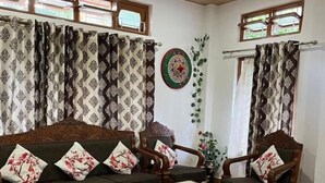 Un salon comprenant un canapé, deux fauteuils, une table basse et un tapis à motifs.
