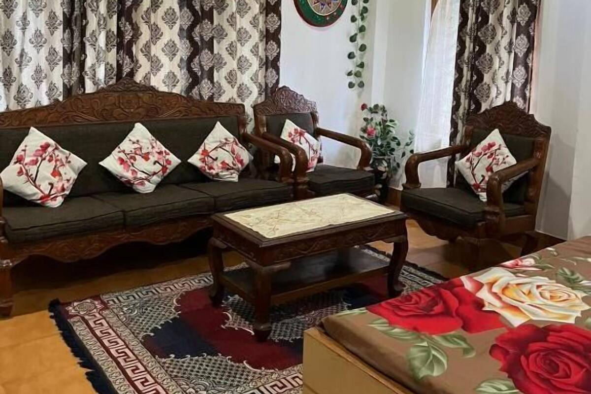 A living room with a sofa set, two armchairs, a coffee table, and a patterned rug.