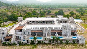 A large, stone building with multiple swimming pools and a courtyard. - The Quila Udaipur by Aayor Luxury (Mavli)