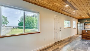 A modern kitchen with wooden flooring, large windows, and a view of the outdoors.