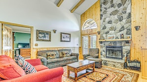 A cozy living room with a fireplace, wooden walls, and a large rug. - 2 Mi to Dtwn: Cloudcroft Home w/ Furnished Deck (Cloudcroft)