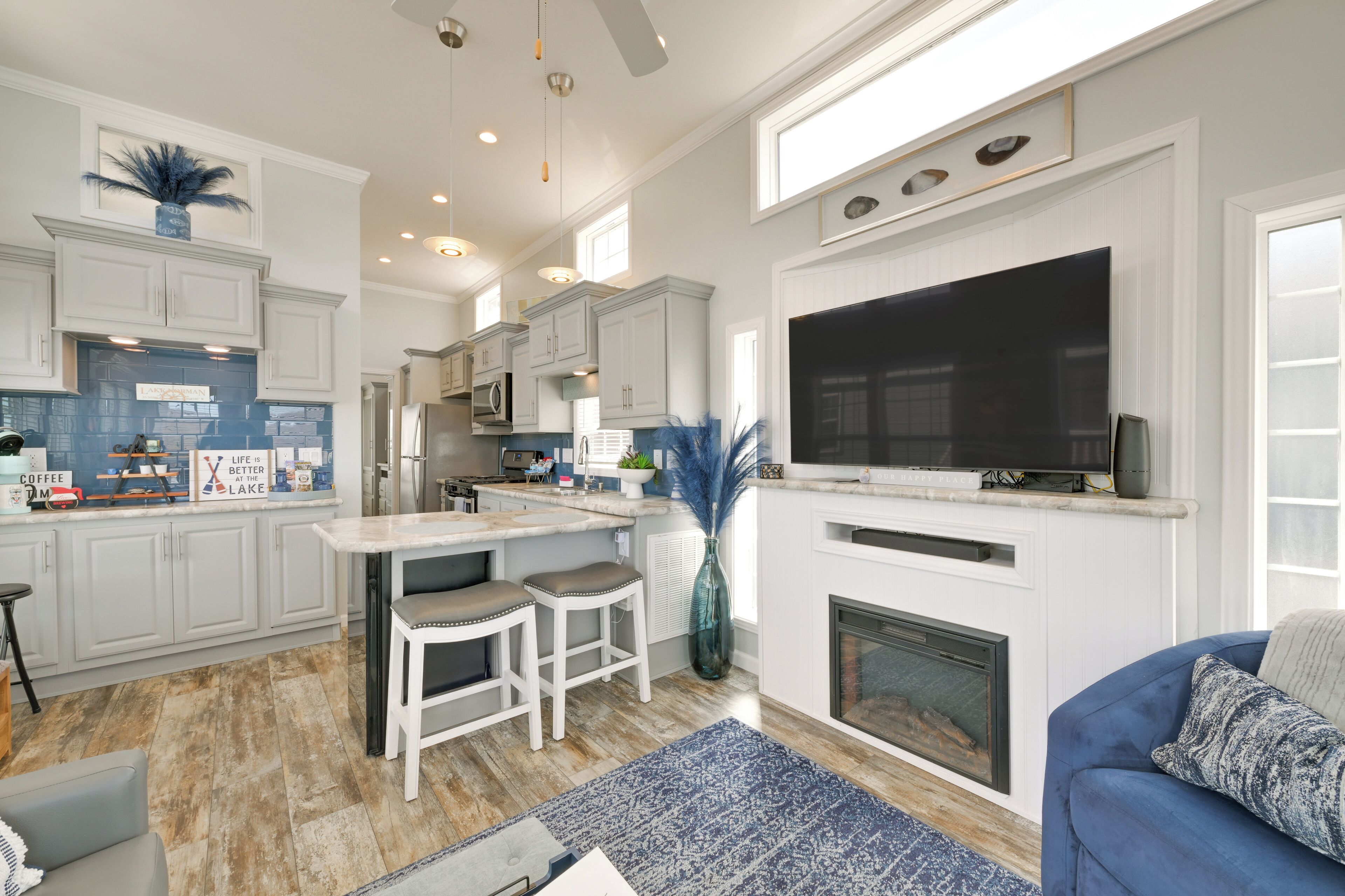 A modern kitchen with white cabinetry, a large TV, and a fireplace.