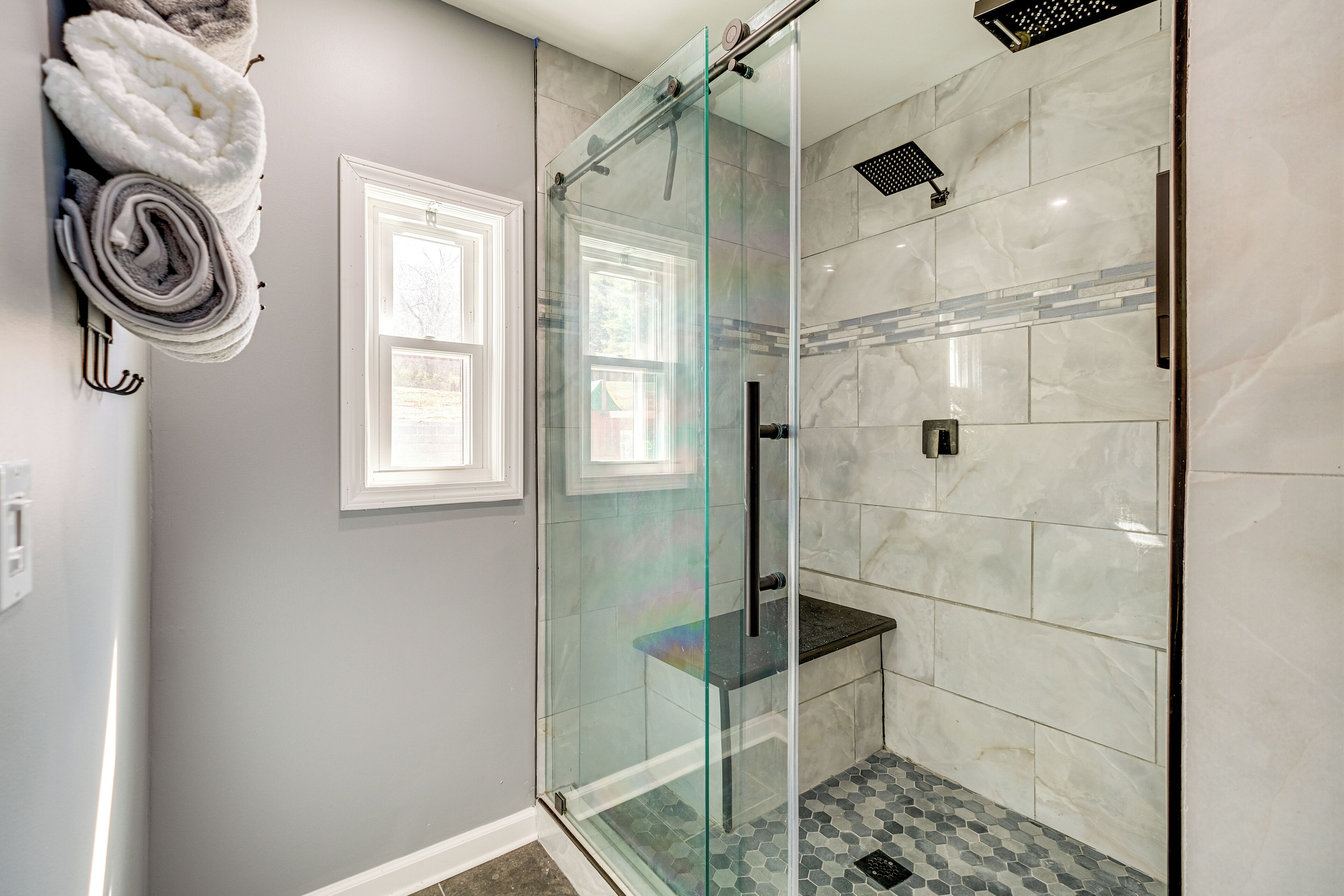 A modern bathroom with a glass-enclosed shower, tiled walls, and a towel rack.