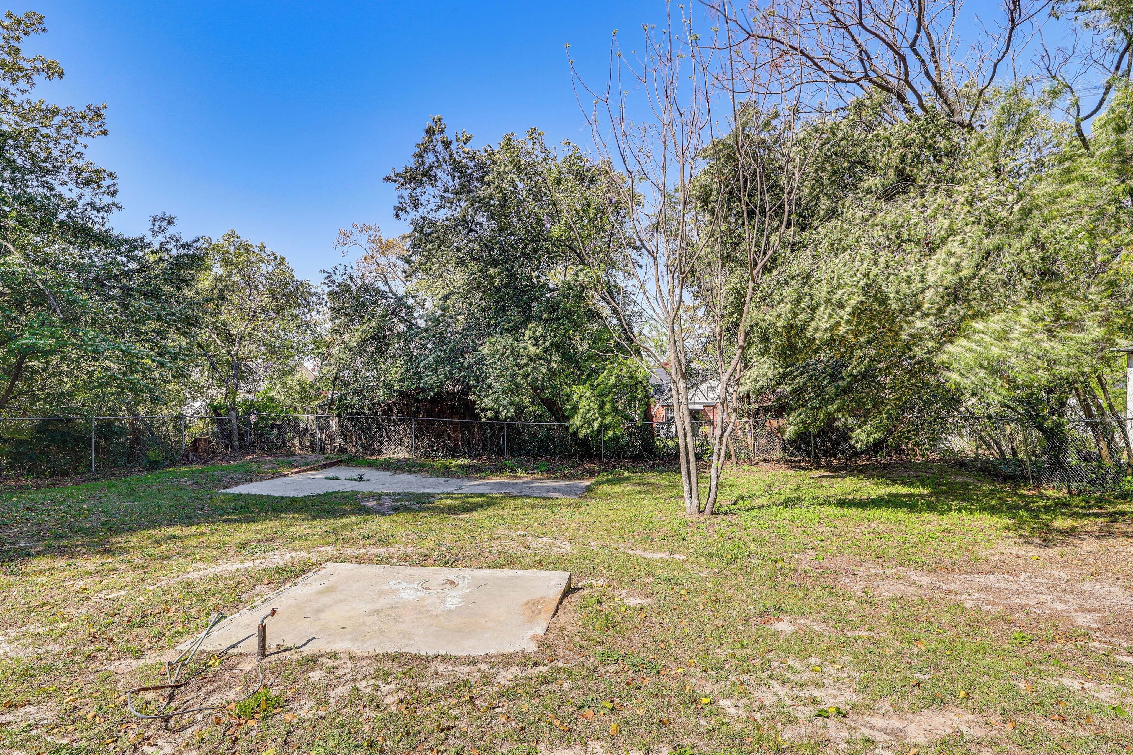 An outdoor area with a concrete slab, grass, and trees.