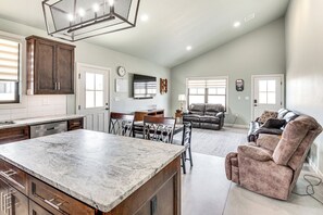 A spacious kitchen with a marble countertop, wooden cabinets, and a dining area with a table and chairs. - Family-friendly Apt w/ Lake Views in Ponca City! (Ponca City)